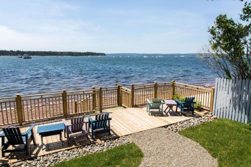 a deck with chairs and tables on the water at Seaside Beach Resort in Saint Andrews