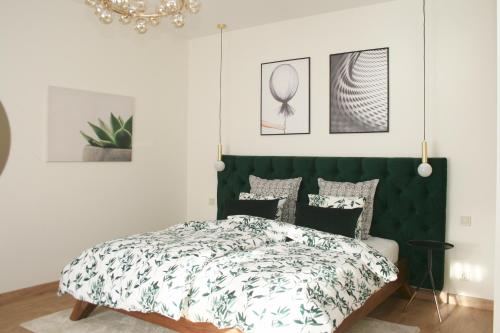 a bedroom with a bed with a green headboard at Elegant apartment in Liepāja