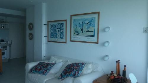 sala de estar con sofá blanco y 2 cuadros en la pared en Apartamento no Porto Real Resort com vista para o mar, en Mangaratiba