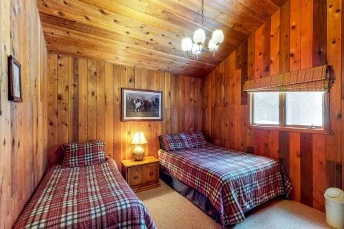 a bedroom with two beds in a wooden cabin at Ponderosa Cabin in Cascade