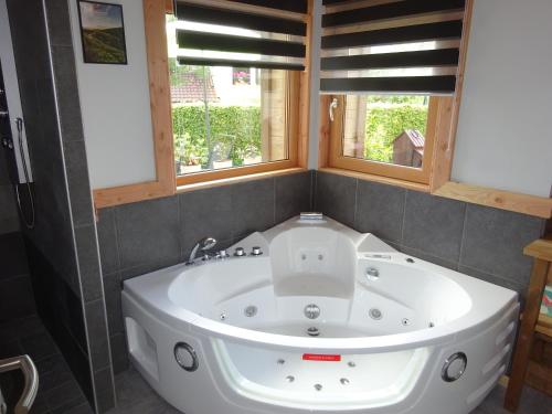 a bath tub in a bathroom with two windows at Chalet la Petite Perle in Gérardmer