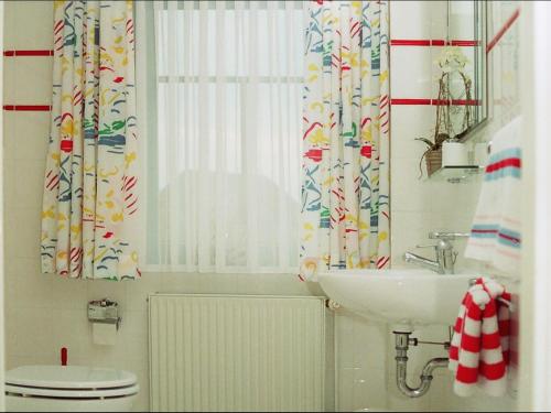 baño con lavabo y aseo y ventana en Ferienhaus Wattenhus, en Büsum