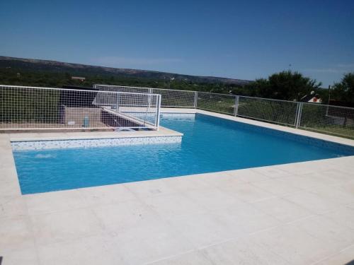 a swimming pool with a fence and blue water at La bendicion in Villa Cura Brochero