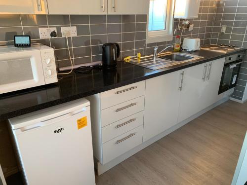 a kitchen with white cabinets and a sink and a microwave at 245 Sundowner in Hemsby