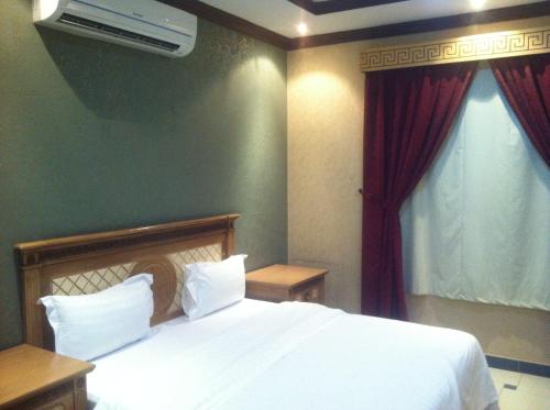una camera da letto con un letto bianco con tende rosse di Makarem Najd Funished Units 2 a Riyad