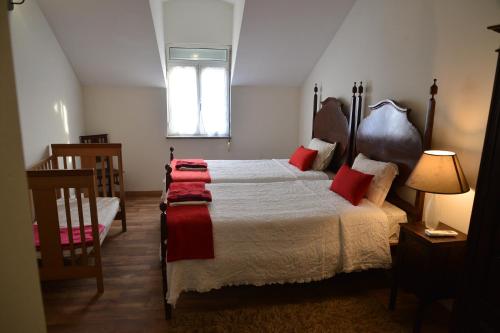 a bedroom with a bed with red pillows and a window at Casa azul in Gouveia