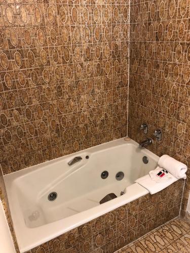 a white bath tub in a bathroom with a tile wall at Days Inn by Wyndham Camarillo - Ventura in Camarillo