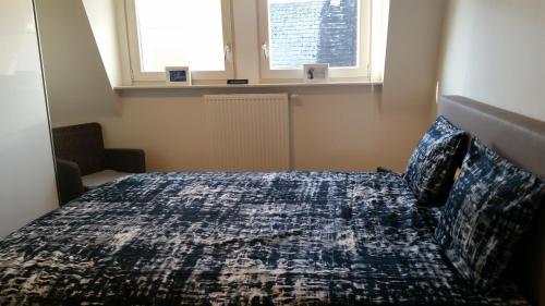 ヘラールツベルヘンにあるAppartement aan De Gaversのベッドルーム1室(ベッド1台、掛け布団、窓2つ付)