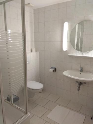 a white bathroom with a toilet and a sink at Winzergarten Hotel-Restaurant in Großkarlbach