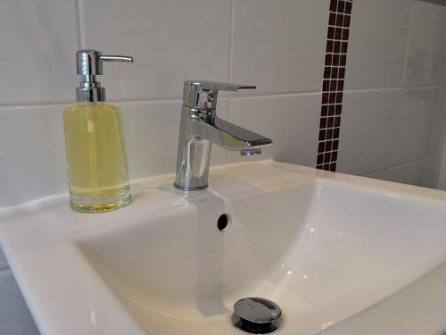 a sink with a bottle of yellow liquid next to a faucet at Duck Cottage in Thirsk