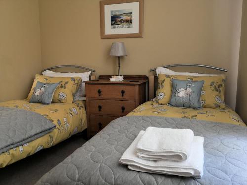 a bedroom with two beds and a dresser with towels at Duck Cottage in Thirsk