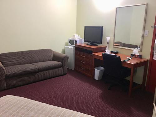 a hotel room with a couch and a desk with a computer at Valley Inn Motel in Sudbury