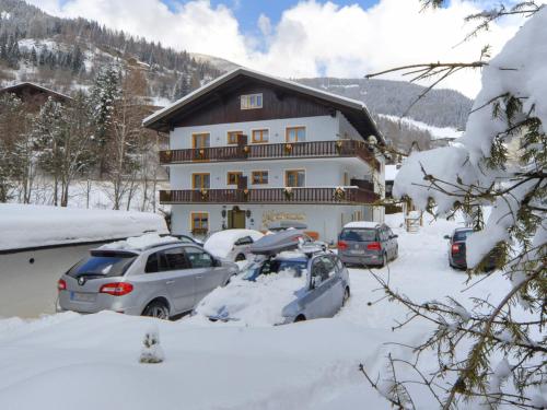 a large house with cars parked in the snow at Pension Isabella in Bad Kleinkirchheim