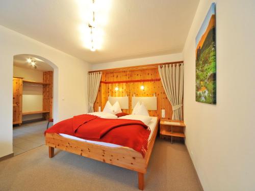 - une chambre avec un grand lit et une couverture rouge dans l'établissement Pension Isabella, à Bad Kleinkirchheim