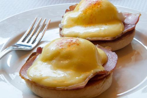 two egg sandwiches with bacon and cheese on a plate with a fork at Ramada by Wyndham Venice Hotel Venezia in Venice