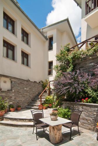 a patio with a table and chairs in front of a building at Iliovolo Guesthouse in Miléai