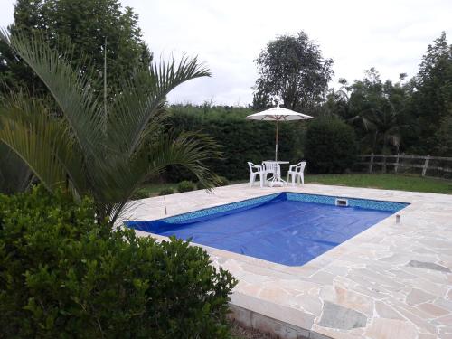 a swimming pool with a table and an umbrella at Estância Liberdade in Santo Antônio do Pinhal