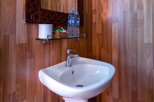 baño con lavabo blanco y pared de madera en Ware Ware Surf Bungalow Lembongan, en Nusa Lembongan