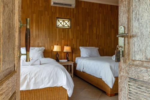 1 dormitorio con 2 camas y ventana en Ware Ware Surf Bungalow Lembongan, en Nusa Lembongan