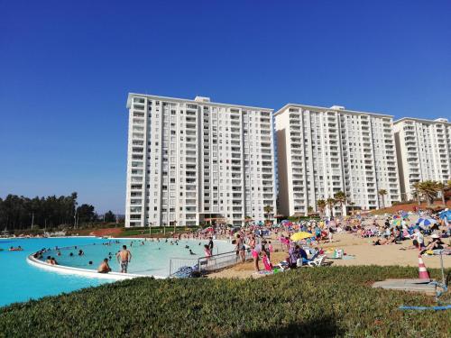 un grupo de personas en una playa cerca de un gran edificio en Departamento Laguna Bahia, en Algarrobo