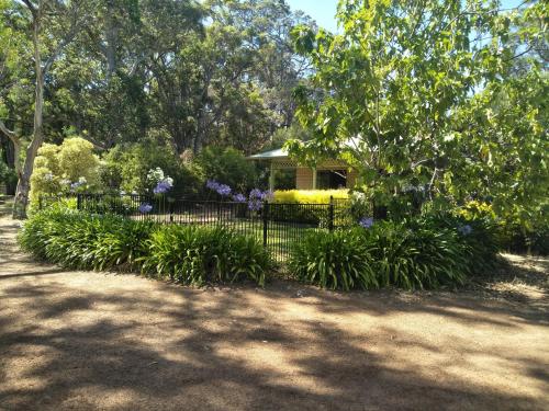 a fence in front of a house with purple flowers at Margaret House in Margaret River Town