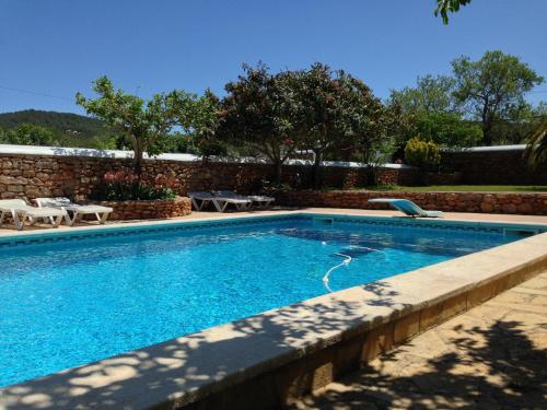 a swimming pool in a yard with a brick wall at Can Gat in Sant Carles de Peralta