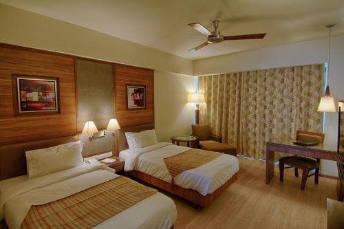 a hotel room with two beds and a desk at The President-A Boutique Hotel in Ahmedabad