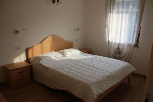 1 dormitorio con 1 cama con colcha blanca y ventana en Residence Elettra, en Crone