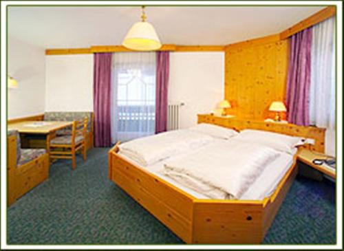 ein Schlafzimmer mit einem großen Holzbett und einem Schreibtisch in der Unterkunft Hotel Sureghes in St. Ulrich in Gröden