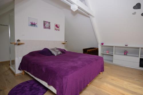 a bedroom with a purple bed with a purple blanket at Gîtes de charme dans l'Essonne in Buno-Bonnevaux