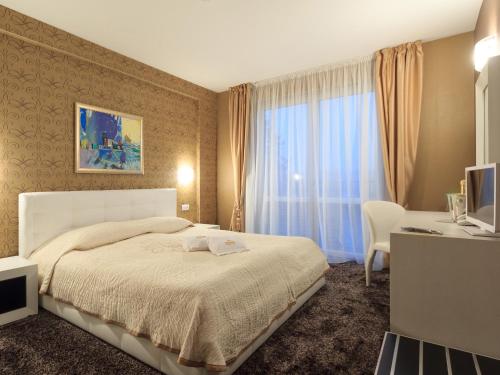 a bedroom with a bed and a desk and a window at Agusta Spa Hotel in Veliko Tŭrnovo