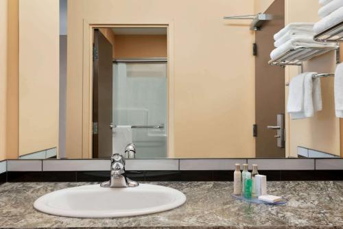 a bathroom with a sink and a large mirror at Travelodge by Wyndham Pincher Creek in Pincher Creek