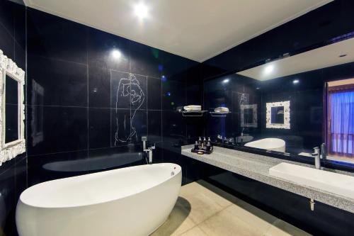 a bathroom with a large white tub and a black wall at White Lotus Villas Seminyak in Seminyak
