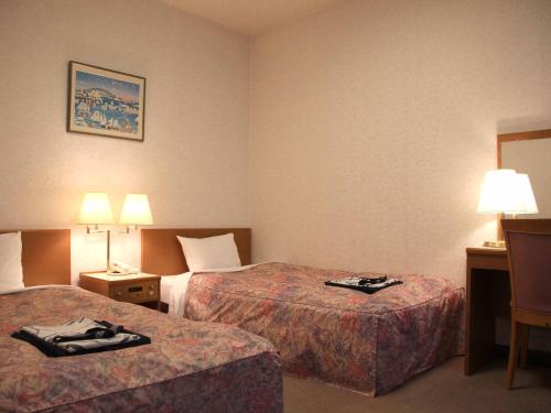 a hotel room with two beds and two lamps at Hotel ab Shiga in Otsu