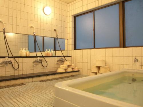a bathroom with a tub and a sink and mirrors at Hotel ab Shiga in Otsu