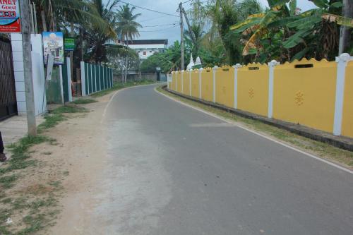 an empty street with a yellow fence on the side of a road at Maduranga n Guest in Mirissa