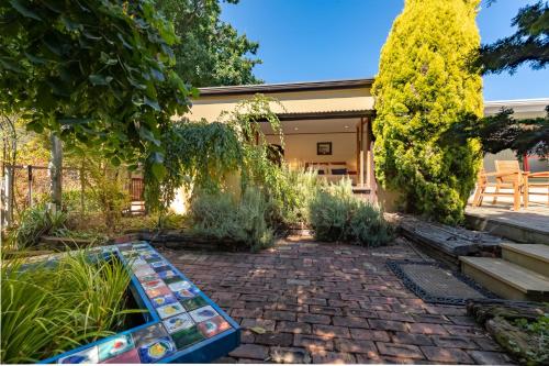 a garden with a brick walkway in front of a house at Shy Cottage and Studio in Greytown