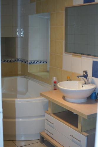 une salle de bain avec une baignoire, un lavabo et un miroir dans l'établissement Le p'tit hameau de Sey, à Quettehou