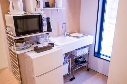 a kitchen with a white sink and a microwave at hirafu188 in Kutchan