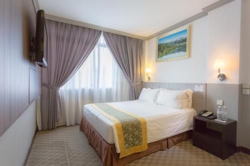 a hotel room with a bed and a window at Hallmark Leisure Hotel in Melaka
