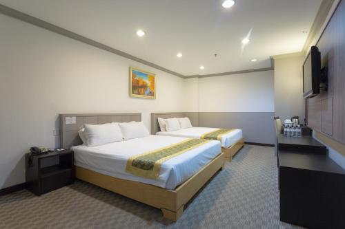 Habitación de hotel con 2 camas y TV de pantalla plana. en Hallmark Leisure Hotel en Melaka