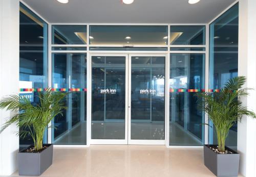 an office building with glass doors and two palm trees at Park Inn by Radisson Jubail Industrial City in Al Jubail