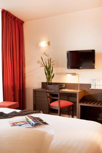 a hotel room with a bed and a desk at Escale Oceania Brest in Gouesnou