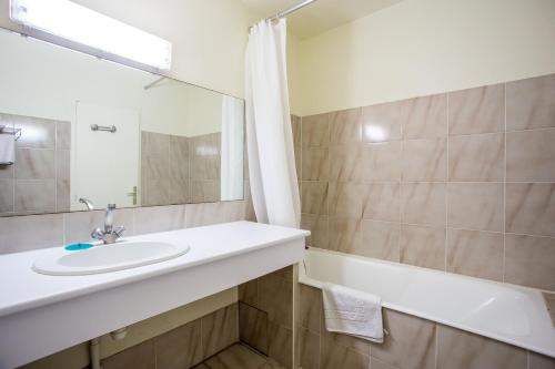uma casa de banho com um lavatório, uma banheira e um espelho. em Hôtel Le Richiardi em Carqueiranne