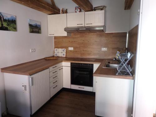 una pequeña cocina con armarios blancos y fregadero en Amsel Haus en Bayrischzell