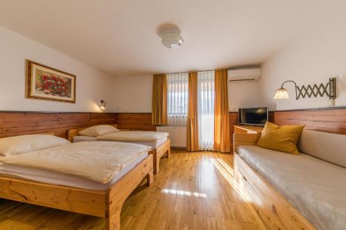 a hotel room with two beds and a couch at Kunstelj Pension in Radovljica