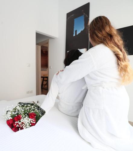 a woman sitting on a bed with a bouquet of flowers at Athenian Residences in Athens