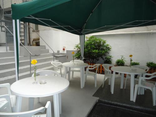 a patio with tables and chairs and a green umbrella at Hotel Adam in Berlin