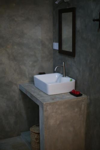 een badkamer met een witte wastafel en een spiegel bij Surfing Wombats in Weligama