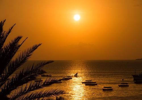 a group of boats on the water at sunset at The Seyyida Hotel and Spa in Zanzibar City